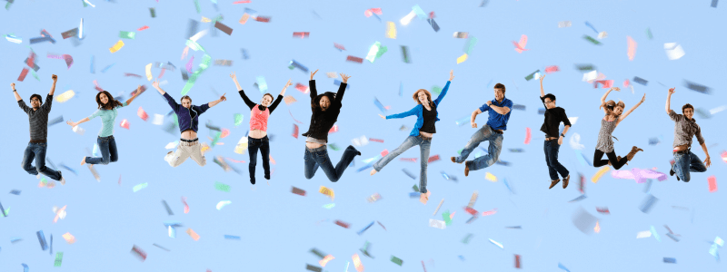 People leaping in the air in front of confetti
